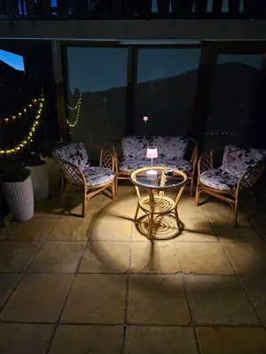 a patio with two chairs and a table with a lamp at Юндовата къща in Beli Iskar