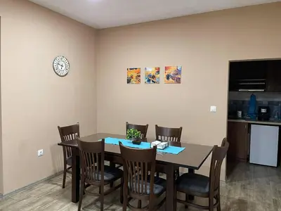 a dining room table with chairs and a clock on the wall at Guest House Marchini in Sapareva Banya
