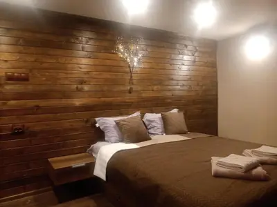 a bedroom with a large bed with a wooden wall at КръчмЪ При Байката in Ribarica