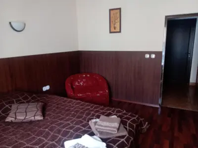 a bedroom with a bed and a red chair at КръчмЪ При Байката in Ribarica
