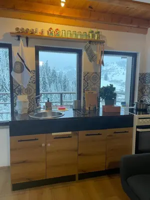 a kitchen with a counter with a sink and two windows at Stoykite Escape House in Stoykite