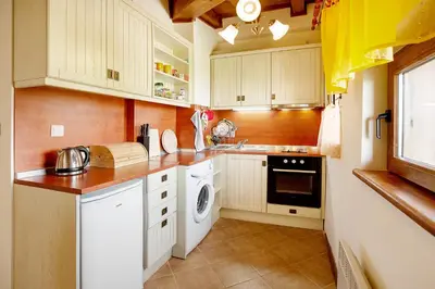 a kitchen with white cabinets and a washer and dryer at Mountain View Pirin Golf in Bansko