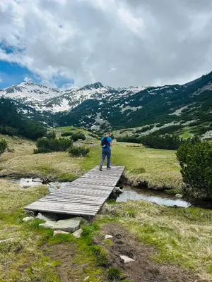 a man standing on a wooden bridge over a river at Na planina in Razlog