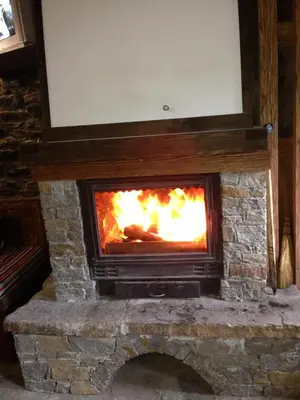 a stone fireplace with a fire in it at Ristevata Guest House in Kovachevitsa
