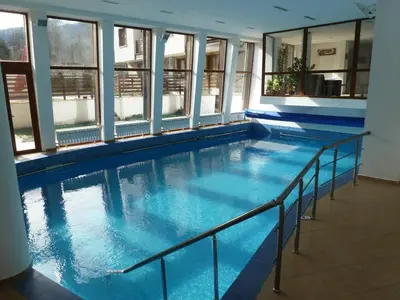 a large swimming pool in a building with windows at Wood Apartment in Mountain View Complex in Bansko