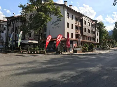 a building with red signs on the side of a street at Wood Apartment in Mountain View Complex in Bansko