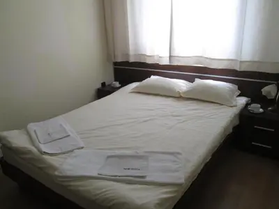 a bed with white sheets and pillows and a window at Fortuna Complex Alexander Services Apartments in Bansko