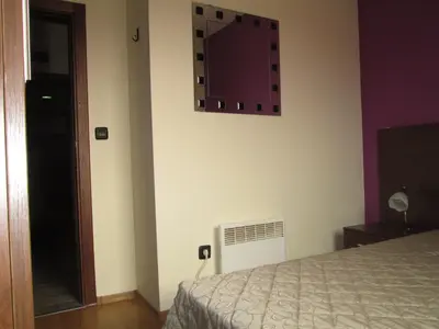 a bedroom with a bed and a tv on the wall at Fortuna Complex Alexander Services Apartments in Bansko