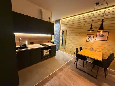 a kitchen with a wooden wall and a table with chairs at Flora Hotel Apartment 103 in Borovets