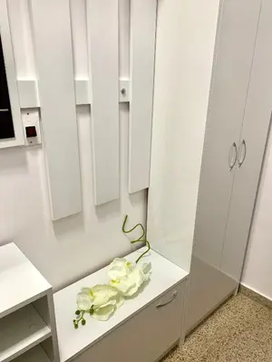 a white kitchen with white cabinets and white flowers on a counter at ,,Адела”-апартамент за гости in Velingrad