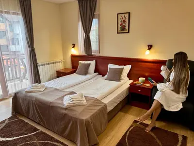 a woman sitting on a bed in a hotel room at Honey House in Bansko