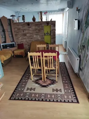 a living room with a table and chairs on a rug at Rila Apartment in Samokov