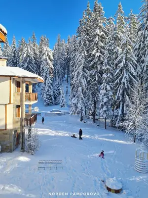 a group of people in the snow near a lodge at NordenPamporovo in Pamporovo