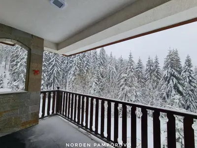 a balcony with a view of snow covered trees at NordenPamporovo in Pamporovo