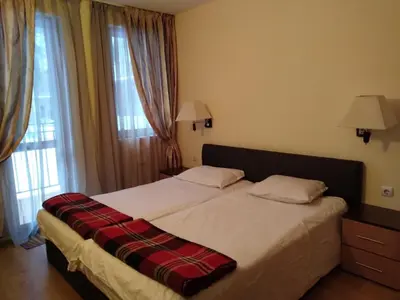 a bedroom with a bed with a plaid blanket on it at Pamporovo Apartment The Castle in Pamporovo