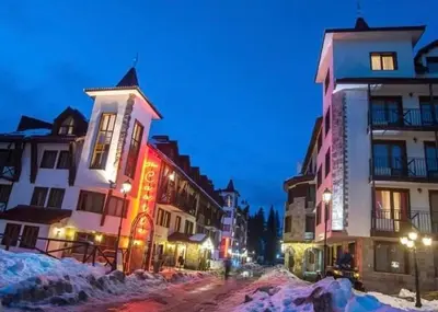 a group of buildings on a snowy street at night at Pamporovo Apartment The Castle in Pamporovo