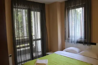 a bedroom with a bed and two large windows at Winter Аpartments Gerovi in Pamporovo