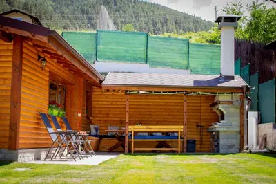 a wooden cabin with a table and chairs in the yard at Villa Boro in Beli Iskar