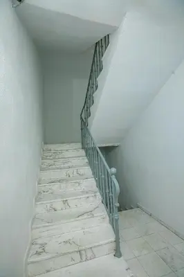 a staircase in a room with white walls and white floors at Aparthouse Heaven in Sandanski