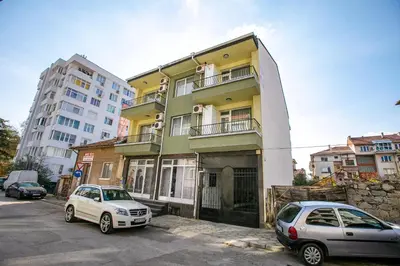 two cars parked in a parking lot in front of a building at Aparthouse Heaven in Sandanski