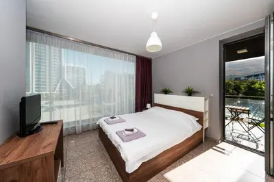 a bedroom with a bed and a tv and a balcony at Modern Apartment 2 with Parking next to Bulgaria Mall in Sofia