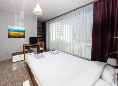 a bedroom with a white bed and a large window at Modern Apartment 2 with Parking next to Bulgaria Mall in Sofia