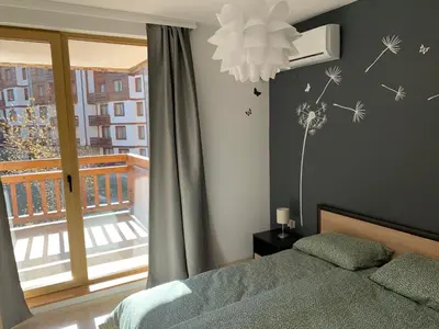 a bedroom with a bed and a window with dandelions on the wall at Premium Apartments Bansko in Bansko