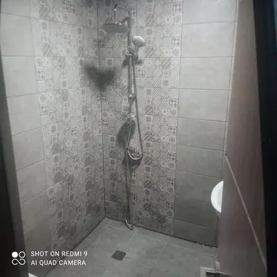 a shower in a bathroom with a tile wall at Къща за гости “Приятели“ in Ovchartsi