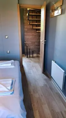 a room with two beds and a stair case at Къща за гости “Приятели“ in Ovchartsi