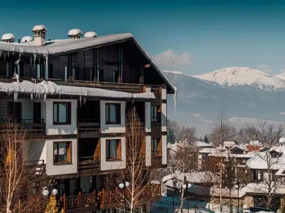 a building with snow on top of it with mountains at Green Life, Bansko, private property in the complex Paradiso Verde, apartman C23 in Bansko