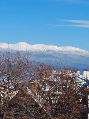 a view of a city with snow covered mountains in the background at Лукс апартамент in Bansko