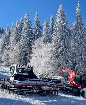 two tractors on a snow plow in front of snow covered trees at Luxury Aparthotel STUDENETS in Pamporovo