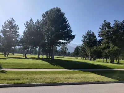 a park with trees and grass and a road at Vintage studio at Pirin golf in Bansko