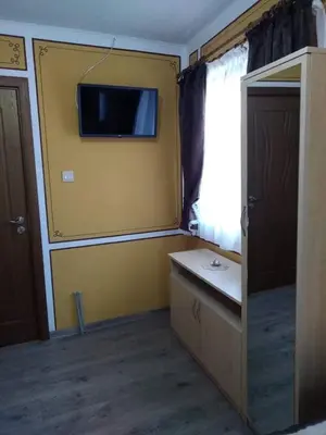 a room with a tv on a yellow wall at Тороманова къща in Koprivshtitsa