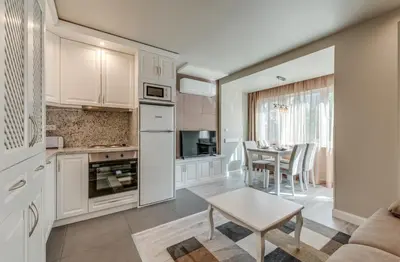 a kitchen with white cabinets and a table and a dining room at R & R Apartments in Sofia