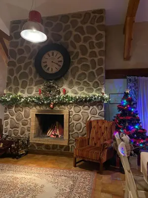 a living room with a fireplace with a clock and a christmas tree at Luxury private studio in Paradiso Verde in Bansko