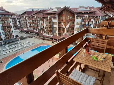 a balcony with a table and chairs and a pool at Bansko Belvedere Apartament in Bansko