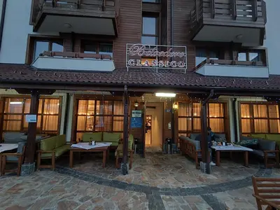 a restaurant with tables and chairs in front of a building at Bansko Belvedere Apartament in Bansko