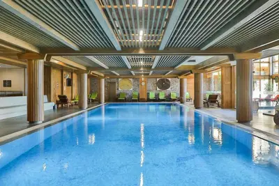 a large swimming pool with blue water in a building at Pirin Golf Hotel Private Studios in Razlog