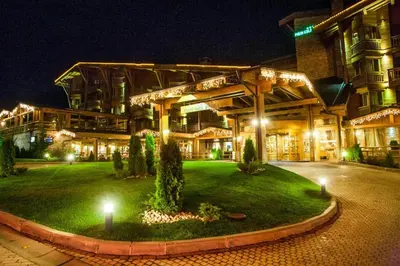 a large building with a green yard at night at Pirin Golf Hotel Private Studios in Razlog
