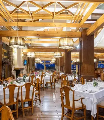 a dining room with tables and chairs and chandeliers at Pirin Golf Hotel Private Studios in Razlog