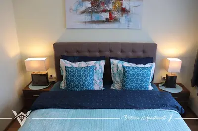 a bedroom with a blue bed with two lamps on tables at Victoria apartments 1 in Velingrad