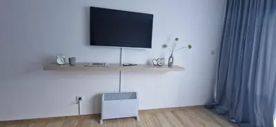 a living room with a tv on a white wall at Free SPA Pirin lodge cosy apartment in Bansko