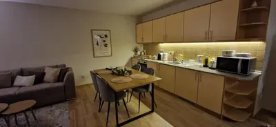 a kitchen and a living room with a table and a couch at Free SPA Pirin lodge cosy apartment in Bansko