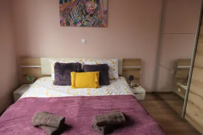 a bedroom with a large bed with purple blanket and yellow pillows at Nikol 2 Deluxe in Velingrad