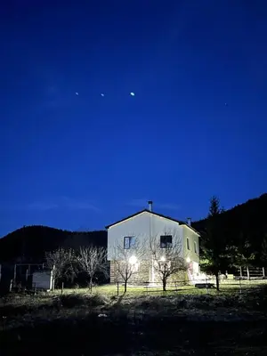 a white barn at night with the moon in the sky at Kassandrov Guest House Ravnogor/ Касандрова къща Равногор in Yasă-Koriya