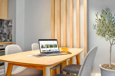 a laptop sitting on a wooden table with chairs at Downtown - Netflix - AC - Next to Metro and Train in Sofia