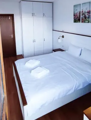 a bedroom with a large white bed with two pillows at Bansko Belvedere Apartments in Bansko
