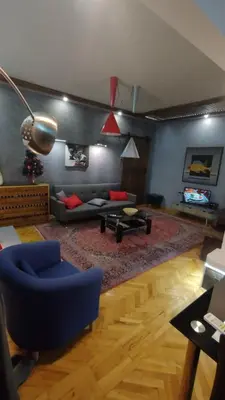 a living room with a blue chair and a couch at Top center Art deluxe apartment near to Aleksander Nevsky cathedral in Sofia