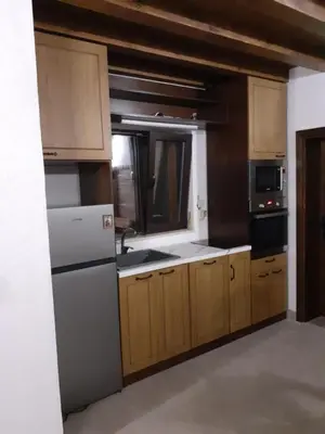a kitchen with a white refrigerator and wooden cabinets at Къща за гости На Мечка in Oborishte